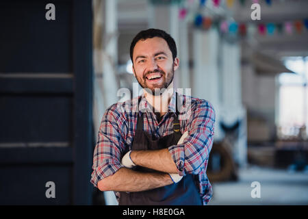 Felice giovane falegname tuttofare in laboratorio, sorridente Foto Stock