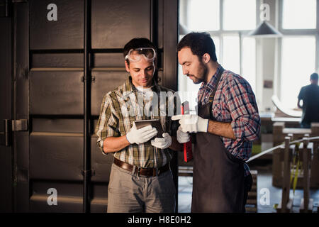 Professione, tecnologia e concetto di persone - due operai con tablet pc computer in officina Foto Stock