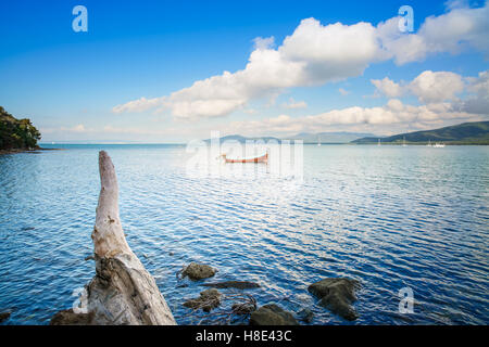 Piccola imbarcazione in legno e il tronco di albero in un mare baia sul tramonto. Punta Ala, Toscana, Italia Foto Stock