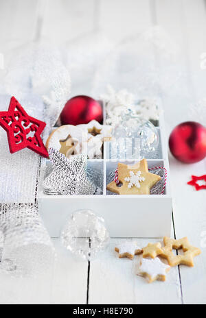 Scatola con biscotti natalizi e decorazioni sul tavolo bianco Foto Stock