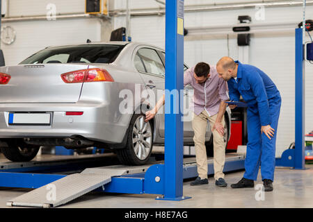 Auto meccanico con un blocco appunti e uomo al negozio di auto Foto Stock