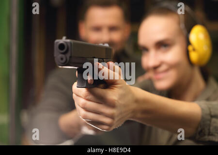 La donna prende lezioni di tiro con la pistola sul poligono di tiro Foto Stock