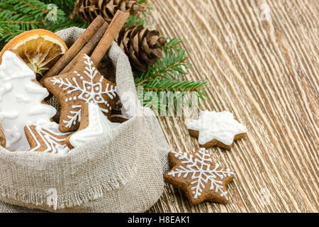 Natale gingerbread cookies nel sacco naturale con ramo di albero marrone su sfondo di legno Foto Stock