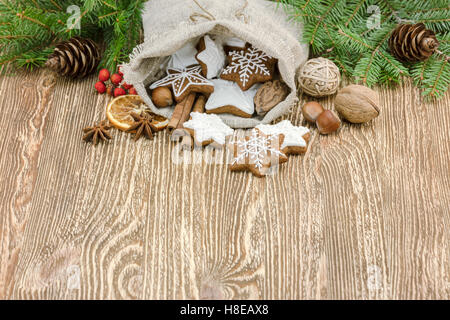 Natale in casa gingerbread cookies nella piccola borsa regalo su sfondo di legno di abete rami Foto Stock