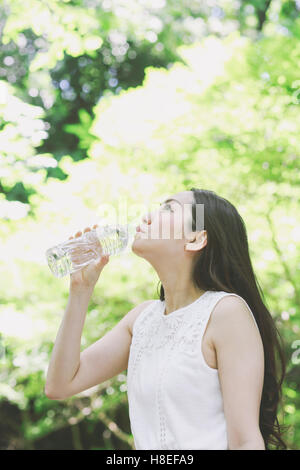 Giovane donna giapponese acqua potabile in un parco della città Foto Stock