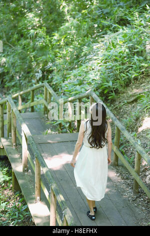 Giovane donna Giapponese circondata da verde in un parco della città Foto Stock