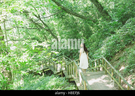 Giovane donna Giapponese circondata da verde in un parco della città Foto Stock