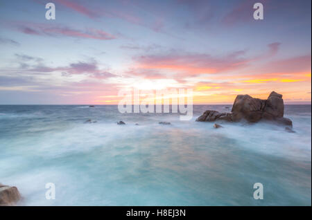 Il Fiery sky telai le onde che si infrangono sulle rocce di Capo Testa a Santa Teresa di Gallura, provincia di Sassari, Sardegna, Italia Foto Stock