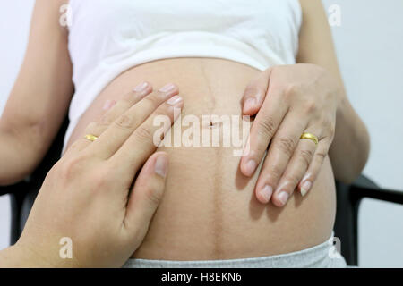 Donne in stato di gravidanza la mano e il marito inseriti a mano sulla pancia concetto di amore per il bambino. Foto Stock