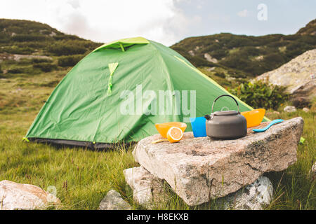 Camping teiera e il tappo sul prato all'orario di alba. Le montagne della Bulgaria. Foto Stock