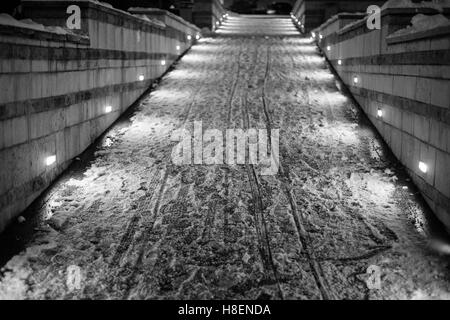 Illuminata strada che conduce verso l'alto e coperto di neve. Immagine in bianco e nero, il fuoco selettivo Foto Stock