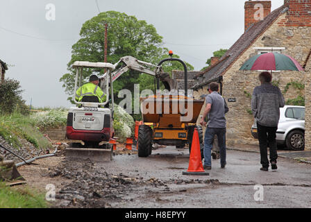 Residenti a piedi passato operai installazione di cavi per superfast a banda larga in un territorio rurale Oxfordshire village, Regno Unito. Foto Stock