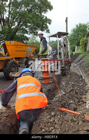 Operai installazione di cavi per superfast a banda larga in un territorio rurale Oxfordshire village, Regno Unito. Mostra i fusti di colore arancione del cavo ottico. Foto Stock
