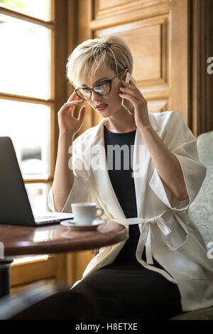 Ragazza colloqui sulla cella in cafe Foto Stock