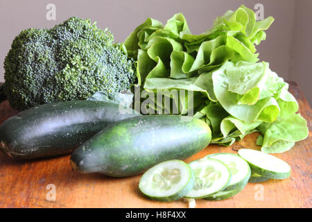 Gruppo di verdure fresche a foglia verde, broccoli, lattuga e cetrioli su un tavolo di legno Foto Stock