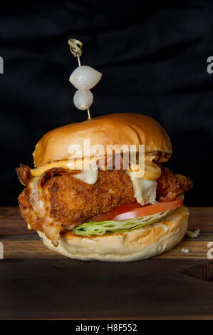 Beefburger e bun con chip (patatine fritte) servita su un tagliere di legno. un REGNO UNITO Foto Stock