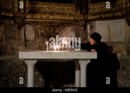 Un pellegrino cristiano accende la candela alla Cappella greca di San Longino il centurione romano che trafitto Cristo e convertito al cristianesimo all'interno della Chiesa del Santo Sepolcro Città Vecchia Gerusalemme Est Israele Foto Stock