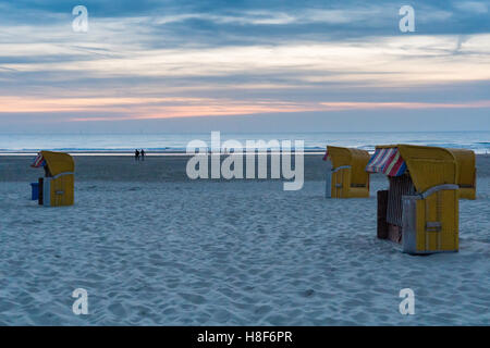 Il giallo di vimini in legno e sedie da spiaggia riposare tranquillamente nella luce della sera su quasi deserta spiaggia a Egmond aan Zee Foto Stock