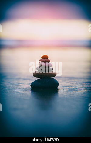 I ciottoli in equilibrio su una spiaggia tempestosa nella luce del mattino con filtro vintage Foto Stock