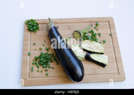Melanzane con le cipolle verdi sul bordo di taglio Foto Stock