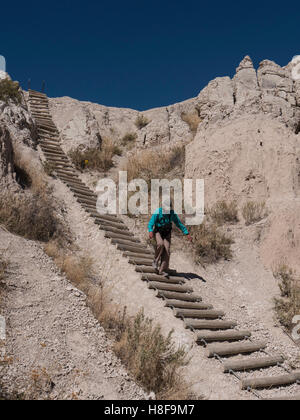 La donna scende la scaletta, tacca Trail, Parco nazionale Badlands, South Dakota. Foto Stock