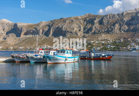 Piccoli pescherecci colorati, Telendos, Grecia, con le isole rocciose dietro Foto Stock