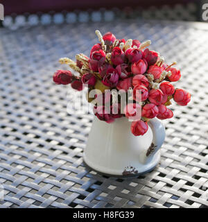 Decorate fiori artificiali con vaso sul tavolo di legno Foto Stock