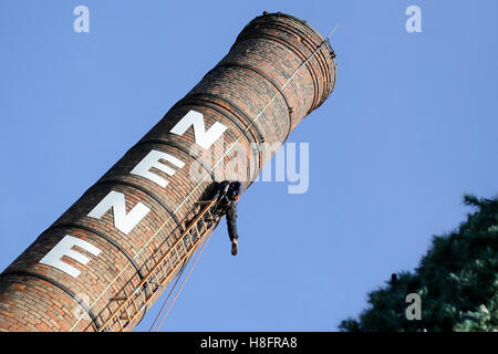 Steeple martinetti lavorando su una molto grande ciminiera in una luminosa giornata di sole Foto Stock