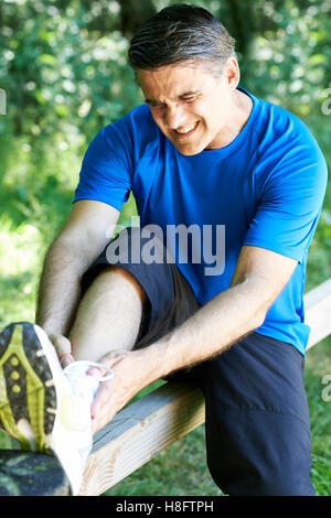 Uomo con sport pregiudizio subito pur esercitando all'aperto Foto Stock