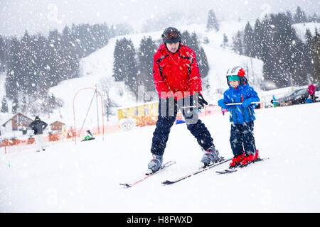 Happy little boy imparare a sciare con il suo padre durante le vacanze invernali nelle Alpi Svizzere Foto Stock