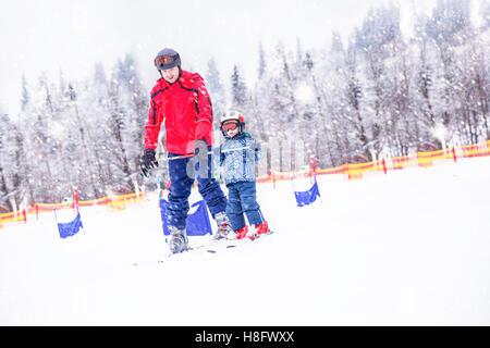 Happy little boy imparare a sciare con il suo padre durante le vacanze invernali nelle Alpi tirolese, Kitzbuhel, Austria Foto Stock