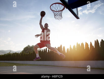 Giovane uomo di salto e facendo un fantastico Slam Dunk giocando stree Foto Stock