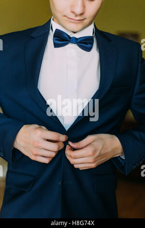 Elegante groom pulsanti sulla elegante vestito blu camicia close up Foto Stock