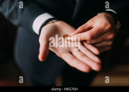 Nozze d'oro anello sul palmo aperto di groom Foto Stock