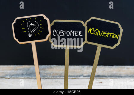 Messaggio di concetto per l'acquisizione di clienti e la lampadina della luce come simbolo per idea scritto con un gessetto su legno mini etichette di Blackboard Foto Stock