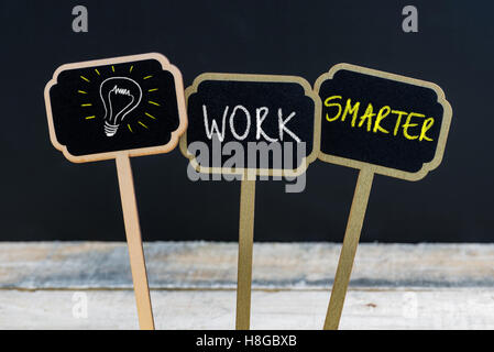 Messaggio di concetto di lavorare in modo più intelligente e lampadina della luce come simbolo per idea scritto con un gessetto su legno mini etichette di Blackboard Foto Stock