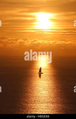 Una barca che si muove attraverso il tramonto del sole a Kata beach, Tailandia Foto Stock