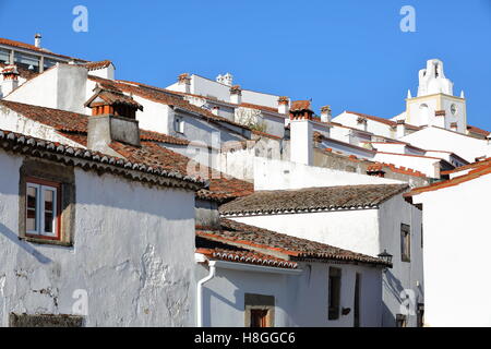 MARVAO, PORTOGALLO: una tipica strada di ciottoli con le sue case dipinte di bianco e tetti di tegole con la Torre dell Orologio in background Foto Stock