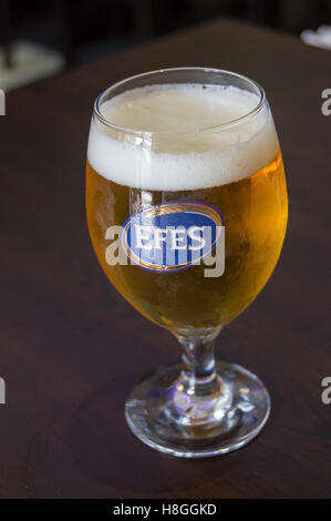 Un vetro stampato di Efes birra turco su un tavolo in un ristorante bar a Londra, Inghilterra, pub tavola bicchieri di bevande Foto Stock