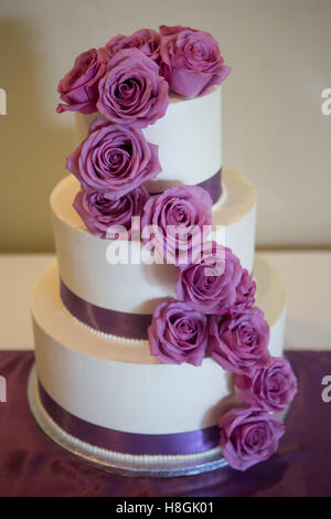 Un multi livello white torta di nozze su base e fiori di colore rosa sulla parte superiore Foto Stock