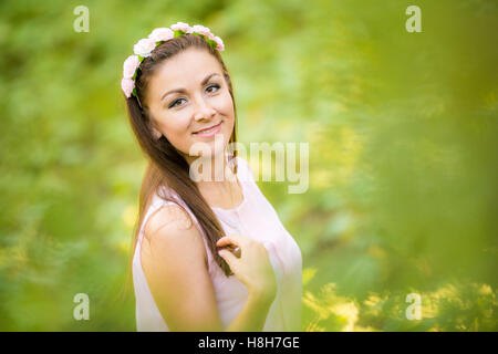 Ritratto di una giovane ragazza bella su uno sfondo sfocato di fogliame verde Foto Stock