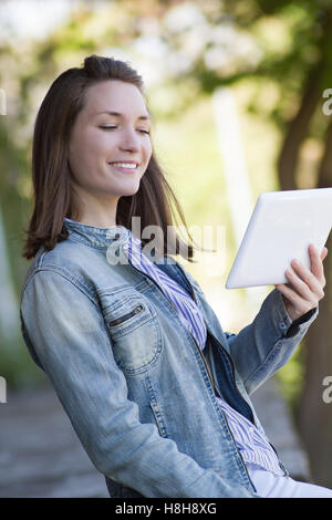 Felice giovane donna con tablet pc all'aperto Foto Stock