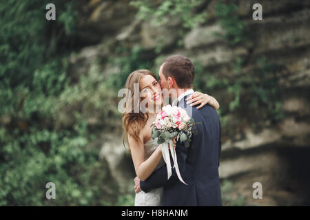 Appena sposato sposi in posa e sposa tenendo in mano mazzo Foto Stock