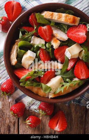 Integratore con insalata di fragole, pollo grigliato, Brie e rucola vicino sul tavolo. vista verticale da sopra Foto Stock