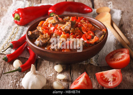 Pezzi di agnello in umido con cipolla, pomodoro e pepe close-up in una ciotola sul tavolo orizzontale. Foto Stock