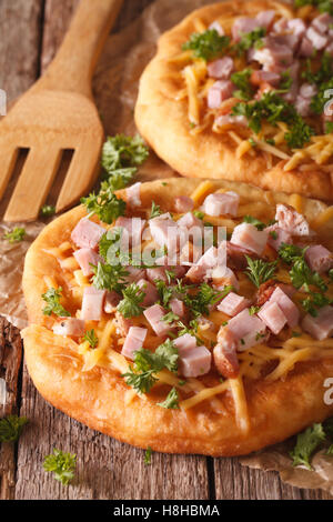 In casa langos ungherese con prosciutto e formaggio vicino sul tavolo. In verticale Foto Stock
