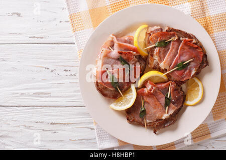 Saltimbocca alla carne bovina con salvia e prosciutto close-up su una piastra. Vista orizzontale dal di sopra Foto Stock