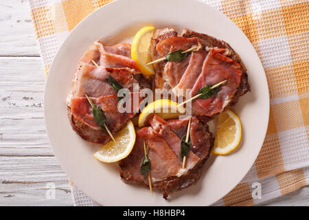 Carne bovina italiana Saltimbocca alla salvia, prosciutto e limone close-up su una piastra. Vista orizzontale dal di sopra Foto Stock