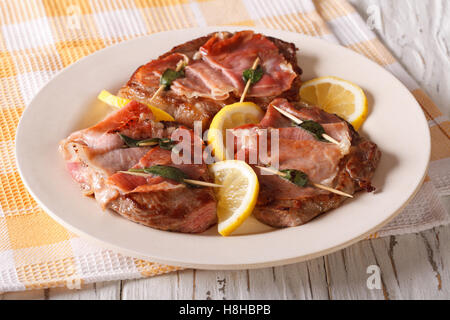 Saltimbocca di Vitello con salvia, prosciutto e fette di limone su una piastra di close-up orizzontale. Foto Stock