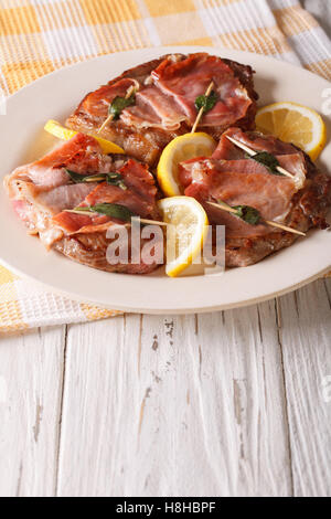 Saltimbocca alla carne bovina con salvia e prosciutto close-up su una piastra. In verticale Foto Stock